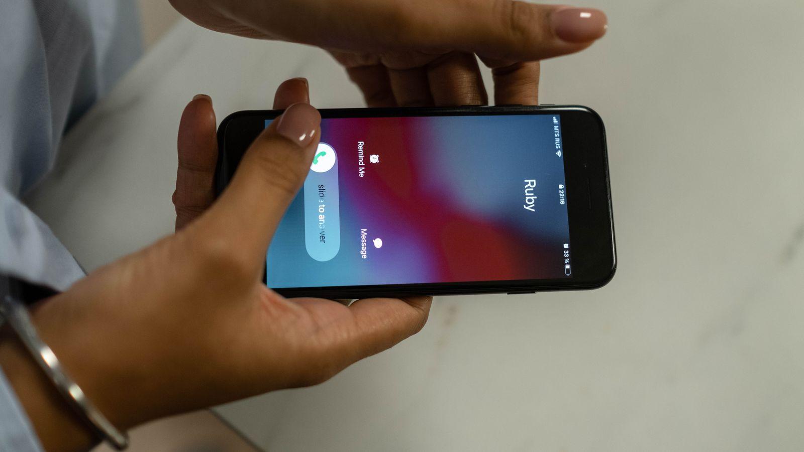 A close-up of a phone screen showing an incoming call labelled "CEO," reflected in someone's glasses in a dim office.