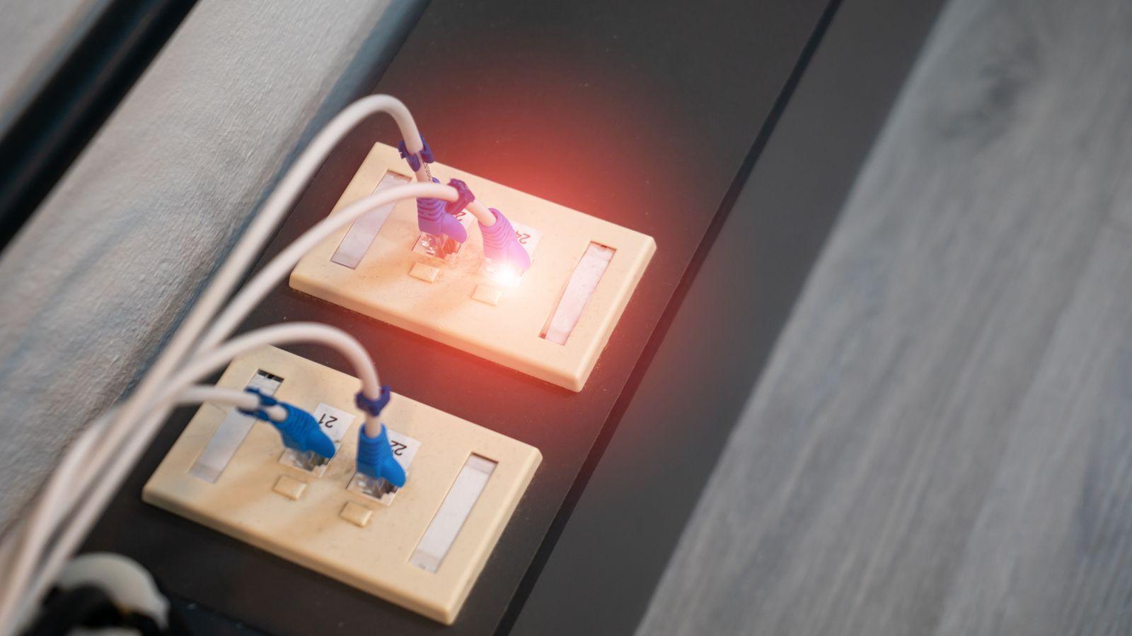 A home router on a shelf with a coffee cup beside it.
