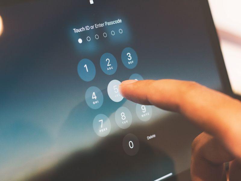 A laptop and a phone on a wooden desk, the phone screen showing a fingerprint prompt and the laptop showing a sign-in page mid-handshake.