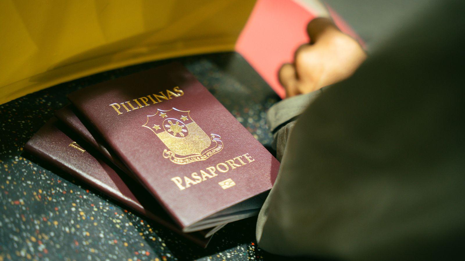 A passport, a YubiKey, and a phone on a wooden surface, laid out for packing.